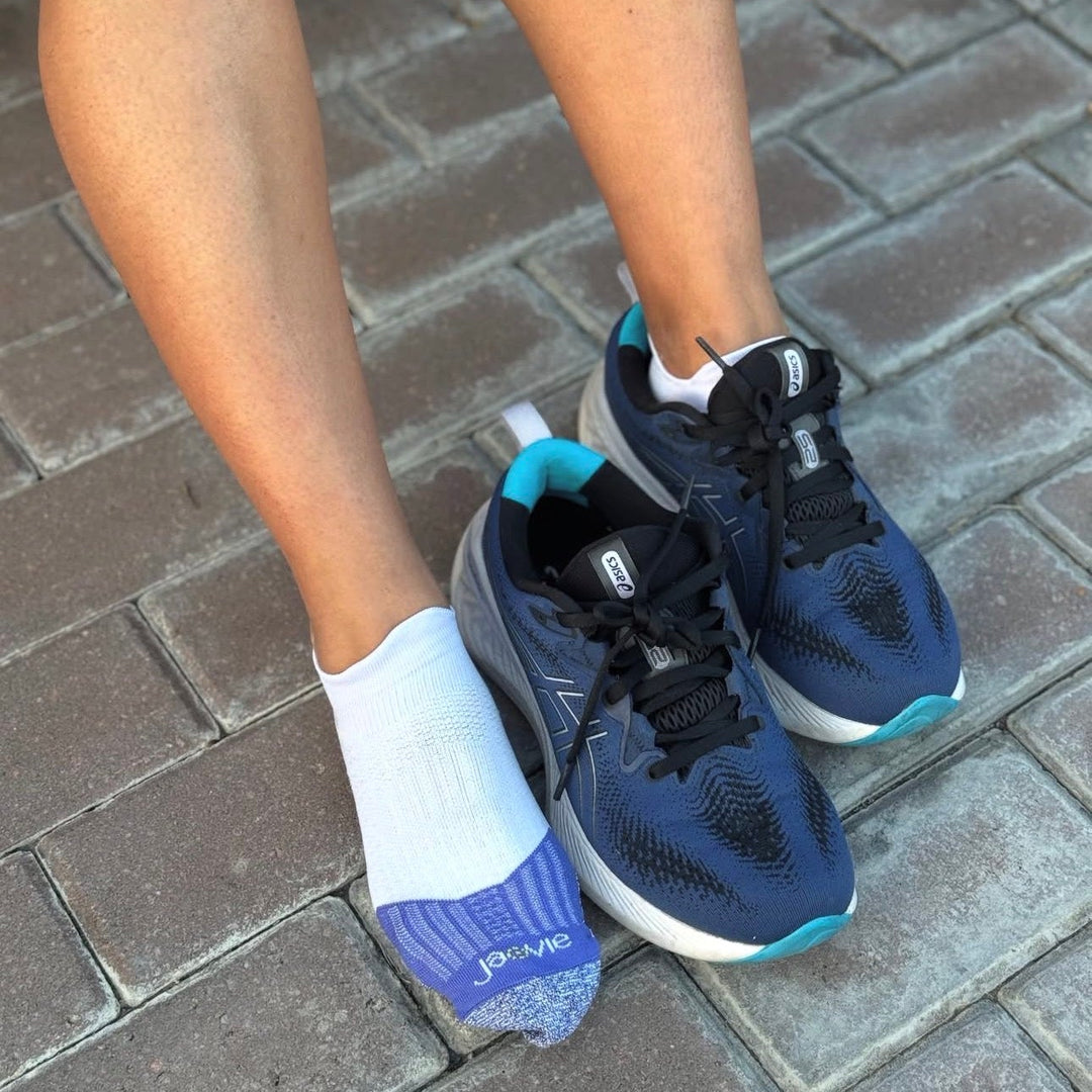 Navy running shoes with white socks on a brick pavement
