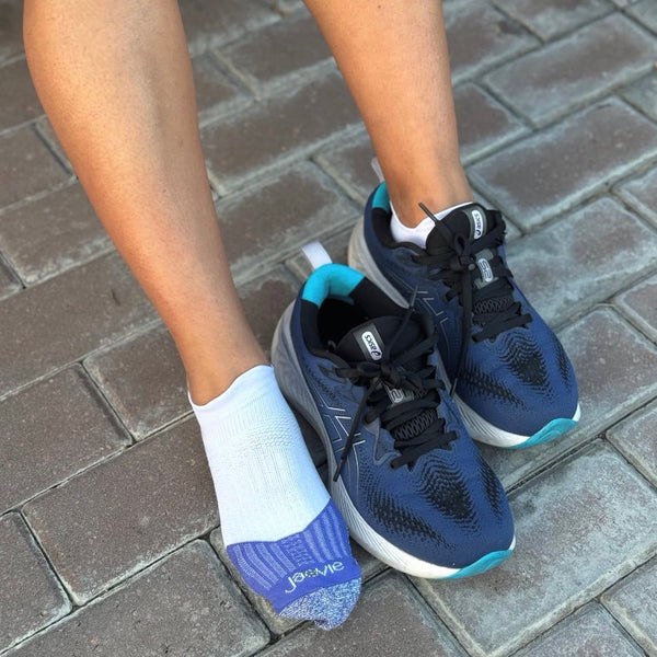 Navy running shoes with white socks on a brick pavement