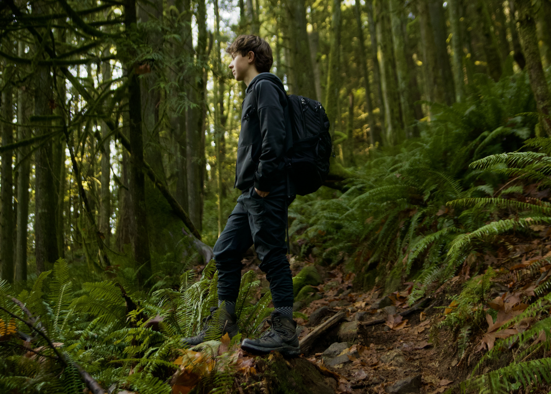 Person hiking through a dense forest with backpack